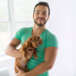 A Young attractive mexican man at home with teckel
