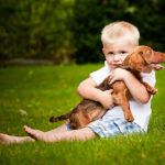 Color image of a little boy holding his puppy.